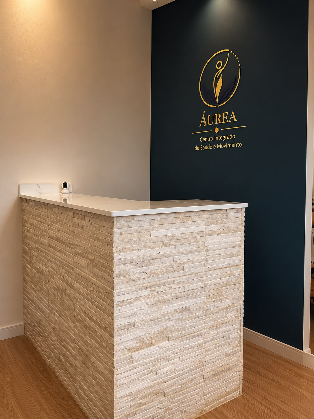 Recepção da Áurea com balcão de pedra e logo dourado na parede azul-marinho