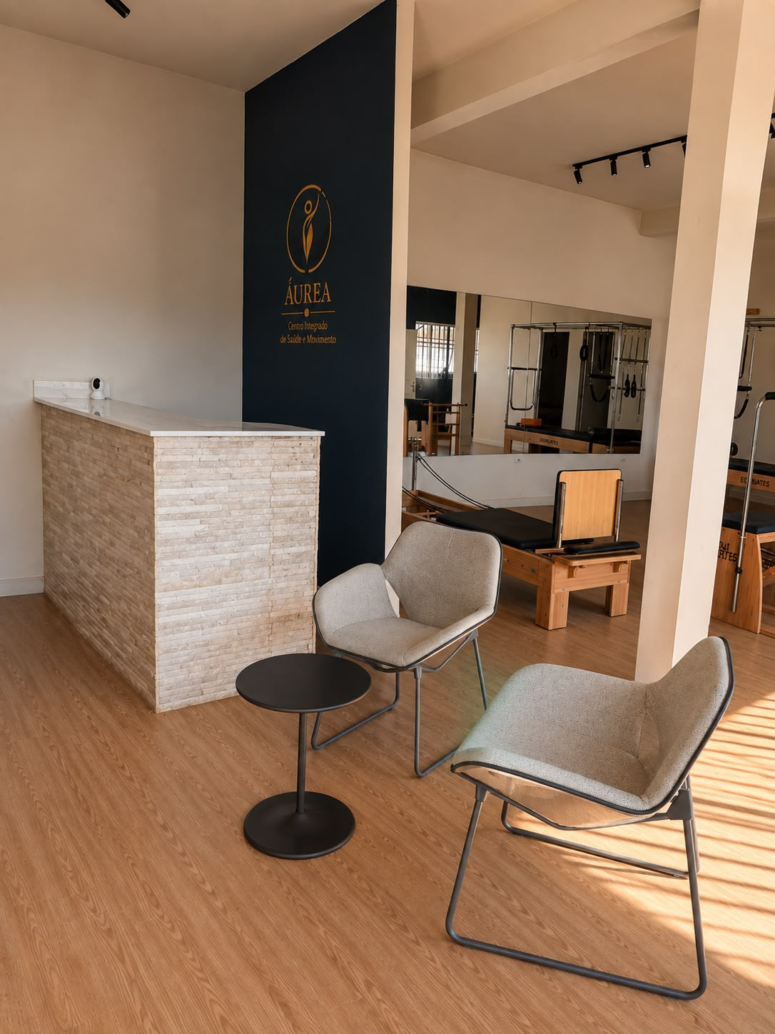 Área de espera com poltronas confortáveis e vista para a sala de Pilates