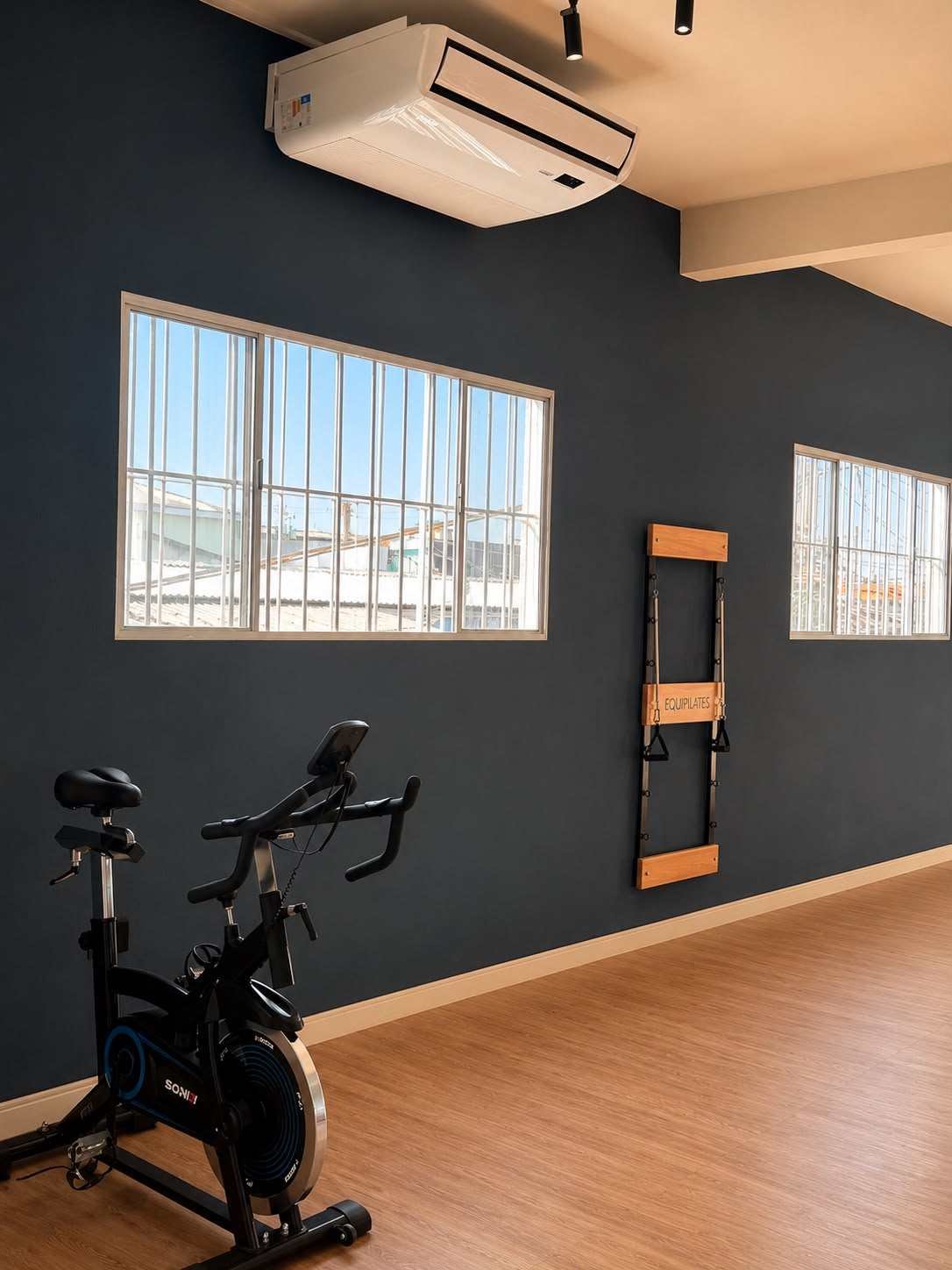 Sala de treino com bike e fita de suspensão em parede azul-marinho